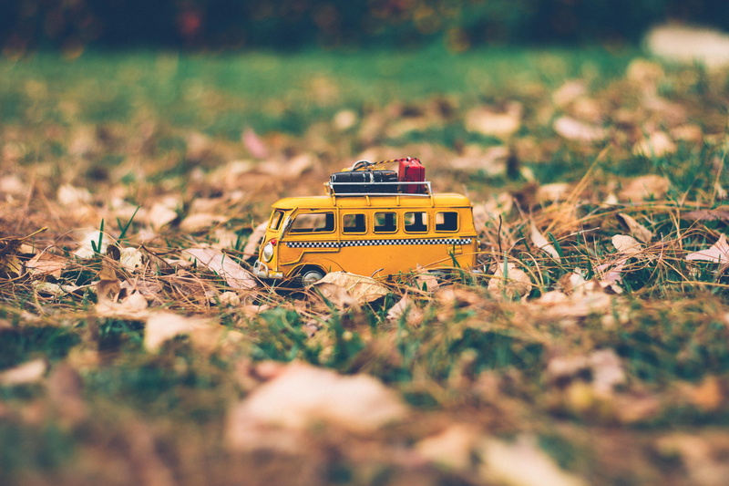 toy, selective focus, blur, yellow, outdoors, model, land, 5K, vehicle, grass, land vehicle, motor vehicle, toy car, bus, day, tilt-shift, scale, field