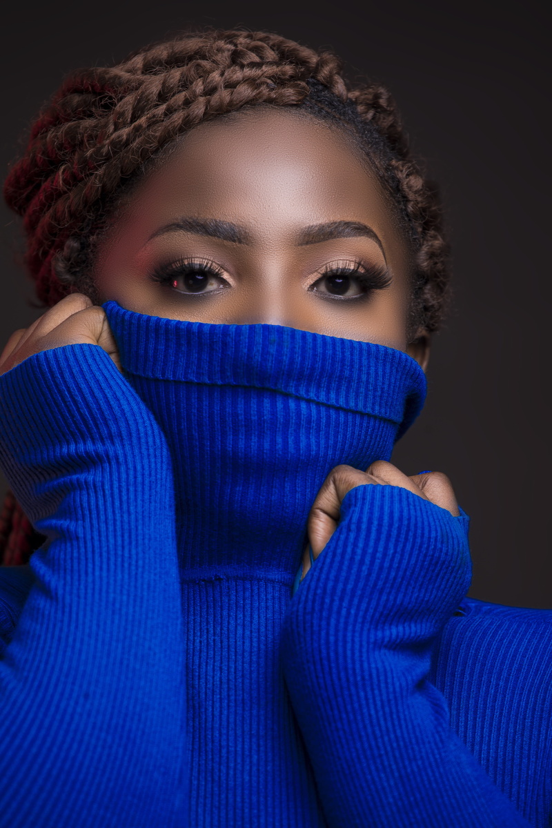 black background, front view, covering, longsleeves, hiding, one person, human face, looking at camera, woman, beautiful, close-up, blue, adult, headshot