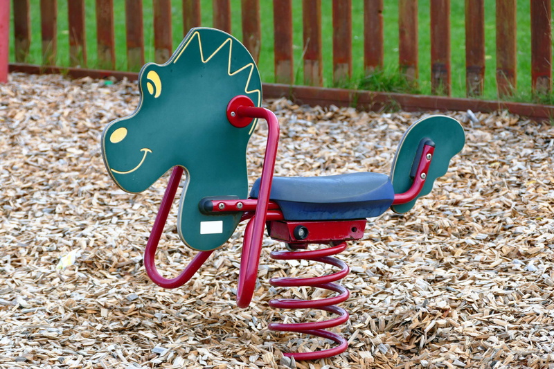 playground, outdoor play equipment, childhood, seesaw, focus on foreground, coiled spring, wheel, grass, spring, red, seat, outdoors, animal representation