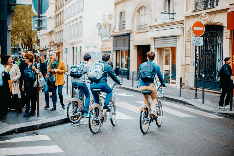 men, real people, leisure activity, riding, sidewalk, 8K, building exterior, bike rider, ride, standing, crowd, group of people, women, active, finance