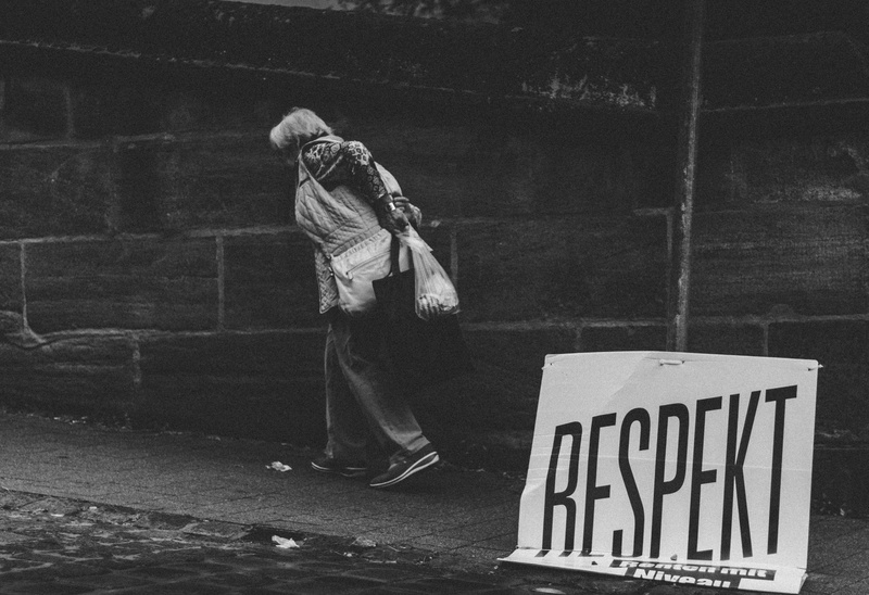 walking, casual clothing, outdoors, black and white, holding, bag, old, poster, plastic, capital letter, wall, real people, text, footpath, white, person