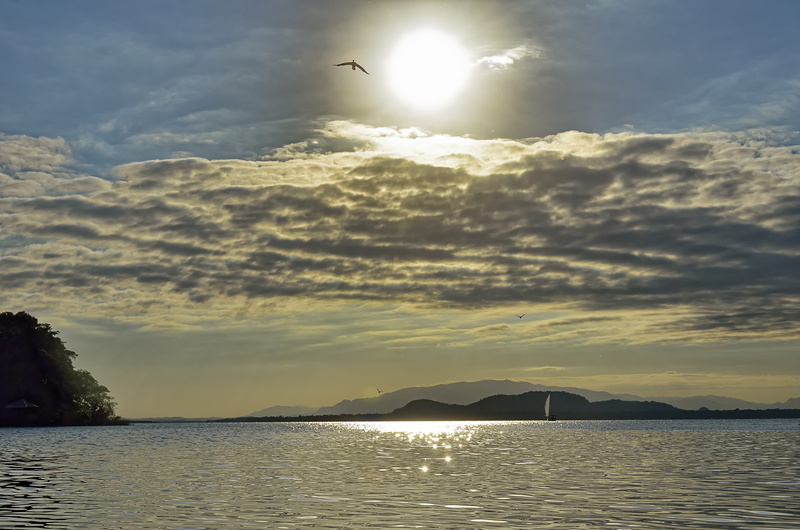 tranquil scene, beauty in nature, scenics - nature, central america, waterfront, silhouette, landscape, sunbeam, cloud - sky, sun, tranquility, rio dulce