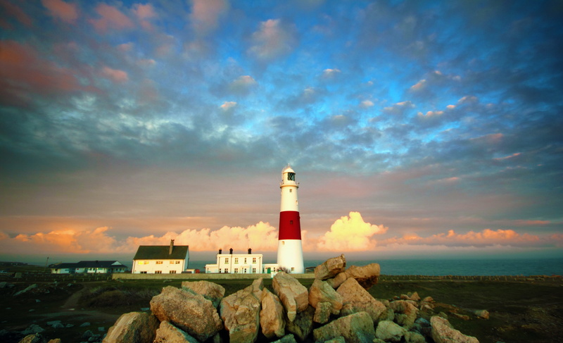 sky, clouds, building, beach, near, solid, rocks, tower, dawn, sea, light, rock - object, red, direction, safety, seashore, guidance, rock, architecture