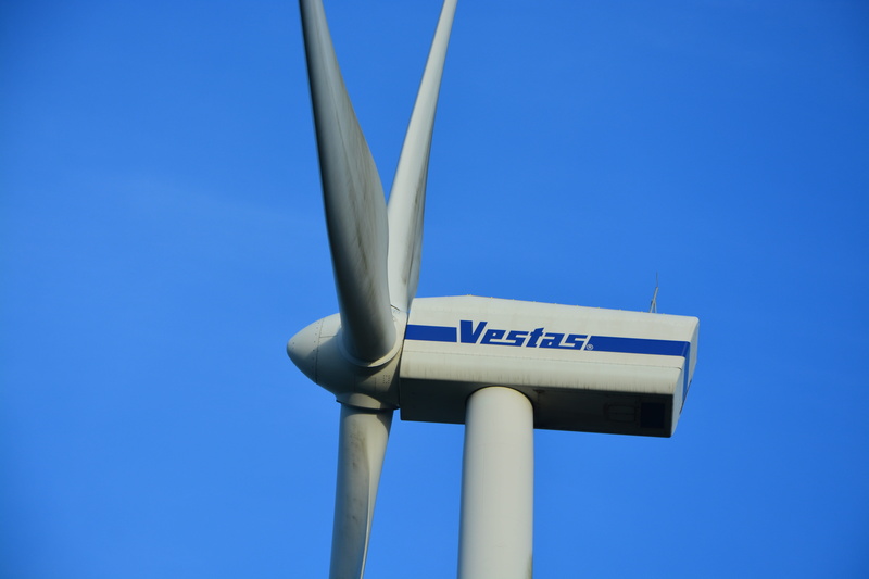 western script, low angle view, directional sign, message, clear sky, text, direction, outdoors, contemporary form, wind turbine, communication, day, arrow symbol