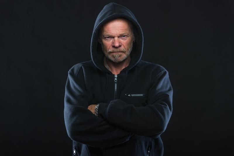 waist up, arms crossed, hood, old, hoodie, bart, indoors, beard, clothing, black background, black, studio shot, mature adult, zip, photo, facial hair