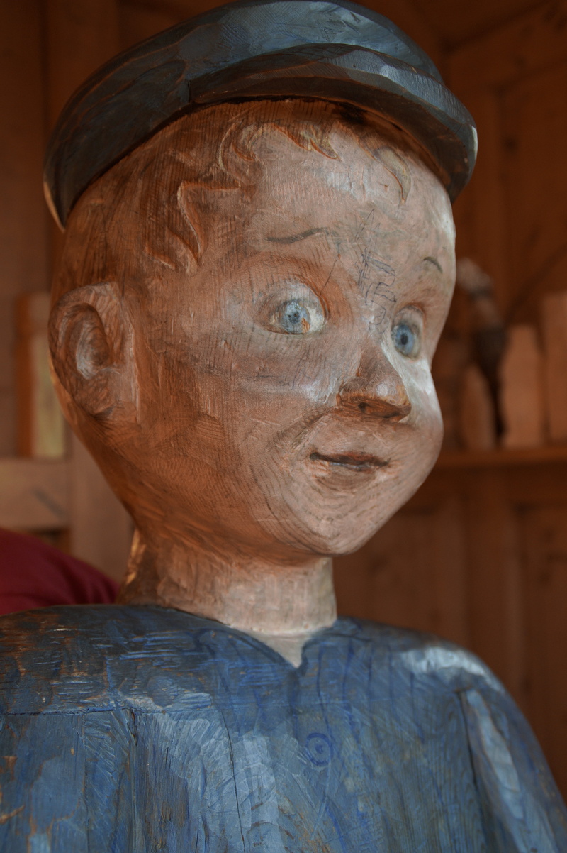 headshot, focus on foreground, mature adult, close-up, lönneberga, one person, tischlerschuppen, childrens book, carving, monument, astrid lindgren, cheeky