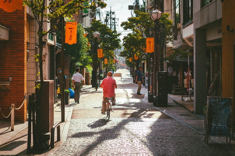mastue, built structure, 2K, sidewalk, filmlike, building, land vehicle, architecture, pavement, riding, adult, group of people, pedestrian, city, people