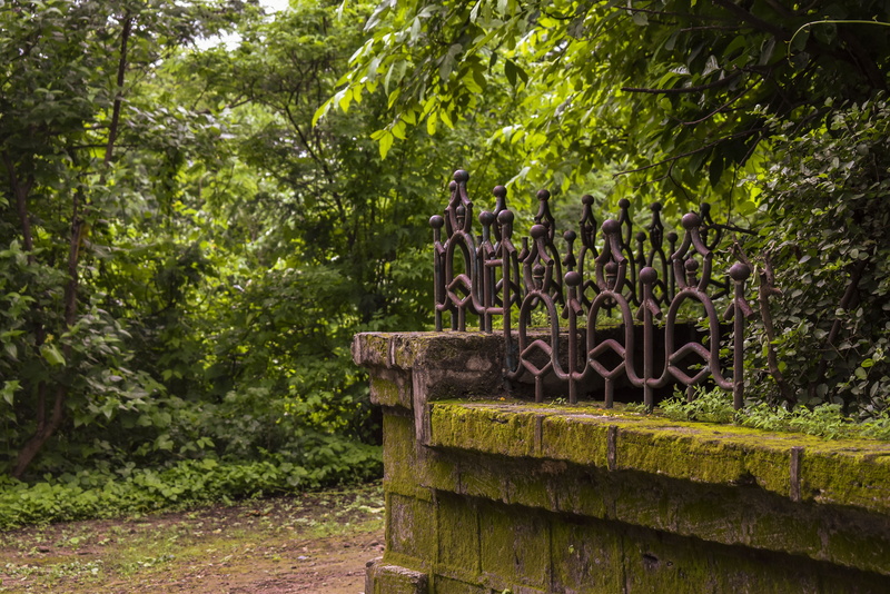 slate, furniture, built structure, clothing, animal, park - man made space, pants, coat, tree, tomb, growth, metal, apparel, plant, bird, text, boundary