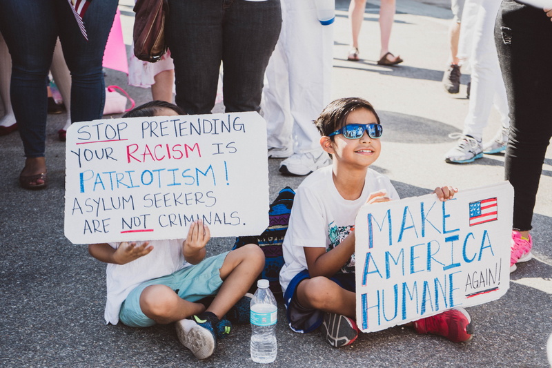 mexican american, group of people, sign, child, casual clothing, kid, women, western script, sits, men, march, 5K, ground, boys, females, holding, communication