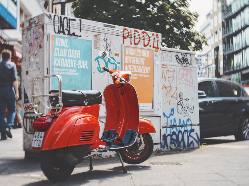 city, outdoors, mode of transportation, germany, sign, non-western script, transportation, communication, orange, köln, script, western script, scooter