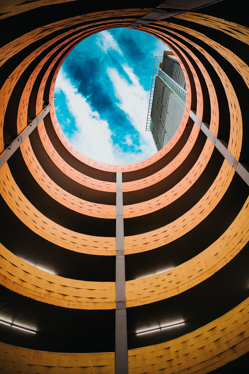 pattern, low angle view, brown, blue sky, concrete, spiral, cloud, urban, no people, labyrinth, cloud - sky, architecture, staircase, city, building exterior