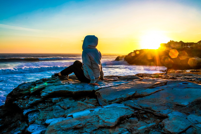 weather, one person, rock - object, sun, city, looking at view, sitting, hairstyle, island, Santa Cruz, solid, recreation, 4K, water, outdoors, scenics - nature