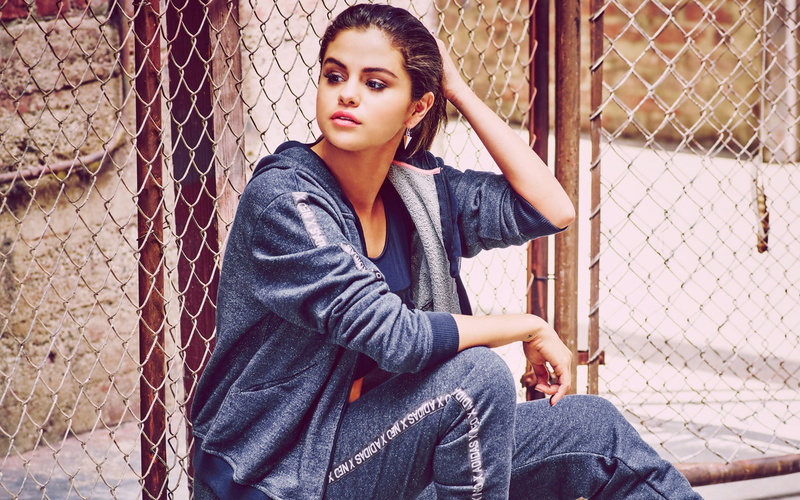 looking at camera, young adult, beautiful woman, 1080P, boundary, chainlink fence, fence, young women, lifestyles, casual clothing, barrier, sitting, leisure activity
