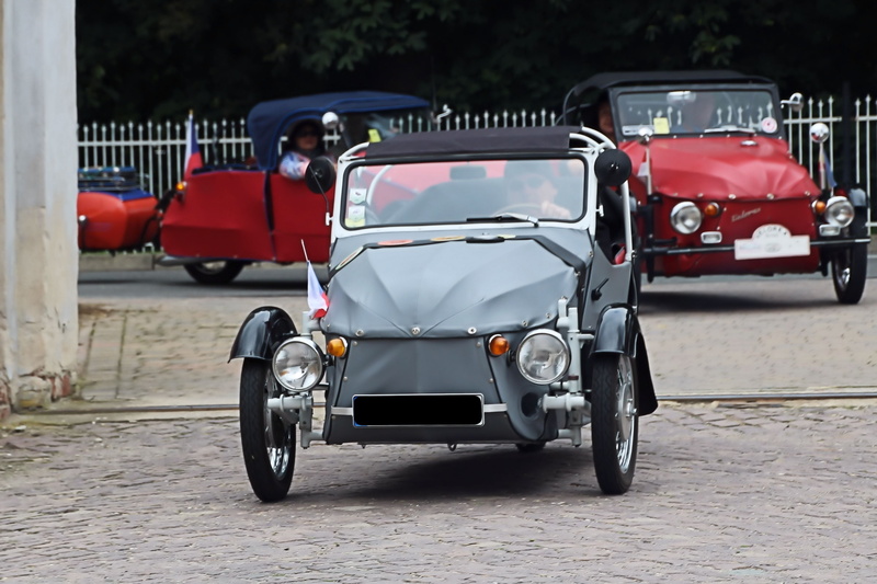 people, os-kar, bicycle, day, old, oldtimer, tricycle, velorex, street, road, city, incidental people, headlight, auto, motor vehicle, driving, architecture