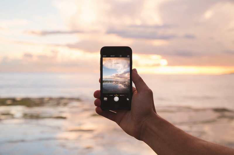 ocean, gray, wireless technology, photography themes, person, holding, summer, island, outdoors, landscape, sky, sunset, s, photography, mobile phone, human body part