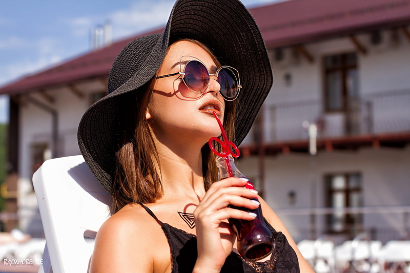hairstyle, model, beautiful woman, clothing, drinking straw, hat, one person, young adult, headshot, brunette, holding, focus on foreground, alcohol, depth of field