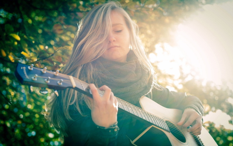 front view, plucking an instrument, girls, fall, hairstyle, jacket, musician, blond hair, string instrument, long hair, playing, one person, nature, blonde