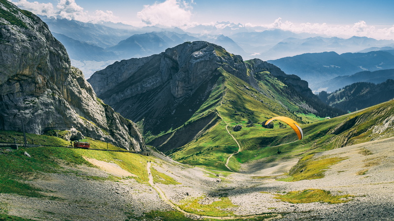 high, clouds, cloud - sky, grass, trees, road, mountain peak, remote, cloudy, scenery, mountain, blue sky, rocks, paragliding, brown, green color, mountain range