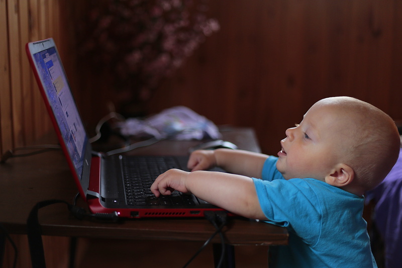 using, lighted, lifestyles, technology, computer, childhood, laptop, wearing, babyhood, real people, one person, blue, t, child, black, young, indoors