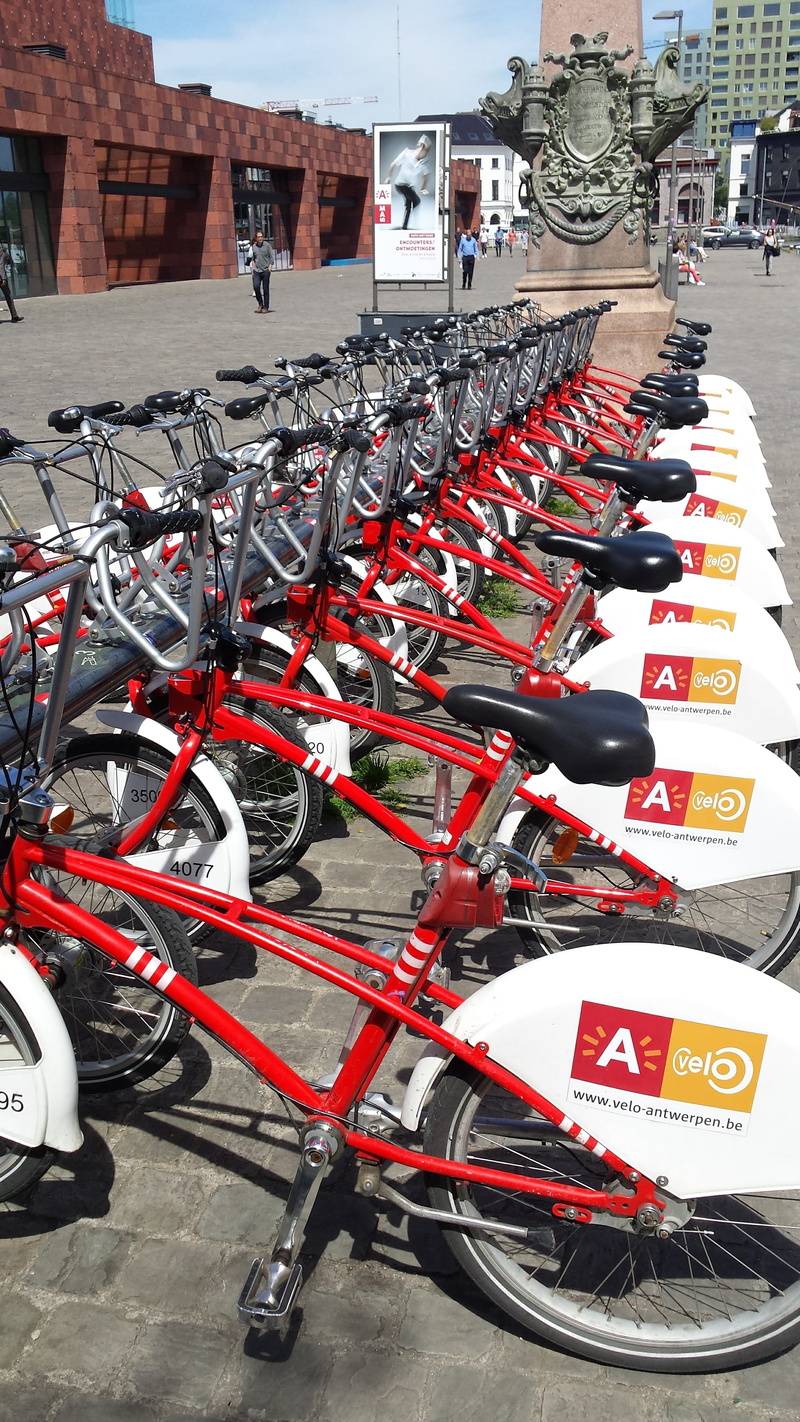 parking lot, antwerp, building exterior, red, incidental people, city Life, outdoors, day, station, wheel, bicycle, car, parking, stabling, belgium, stationary