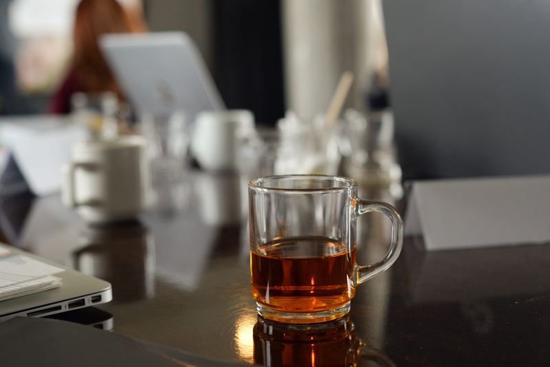 focus on foreground, lap top, papers, glass, table, business, indoors, refreshment, technology, food and drink, cup, tea, beverage, glass - material, bar