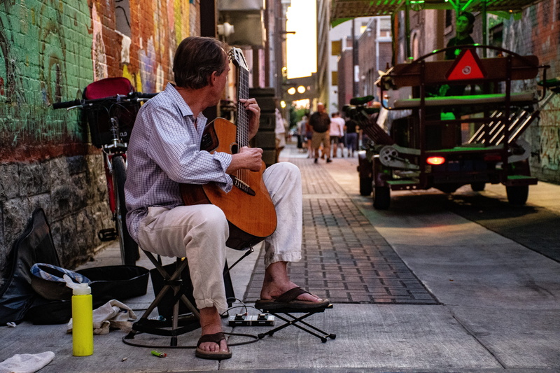street performer, rear view, wall, 5K, road, vehicle, one person, guitar, street, alley, architecture, urban, real people, playing, city, man, graffiti