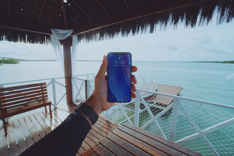 one person, portable information device, lake, real people, architecture, human hand, iphonex, water, human body part, mobile phone, technology, outdoors