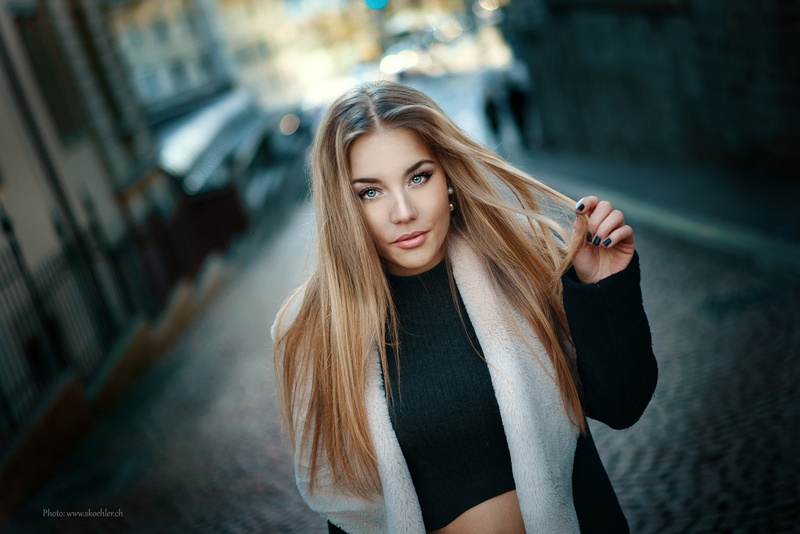 women outdoors, 1080P, touching hair, Public, straight hair, women, model, looking at viewer, holding hair, blonde, black coat, portrait, black tops, long hair