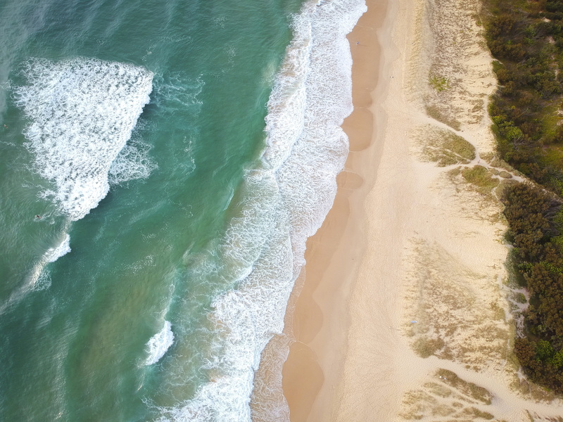 top view, tranquility, beauty in nature, coast, outdoors, waves, power in nature, surfing, high angle view, water, birds eye view, beach, sport, land, drone shot