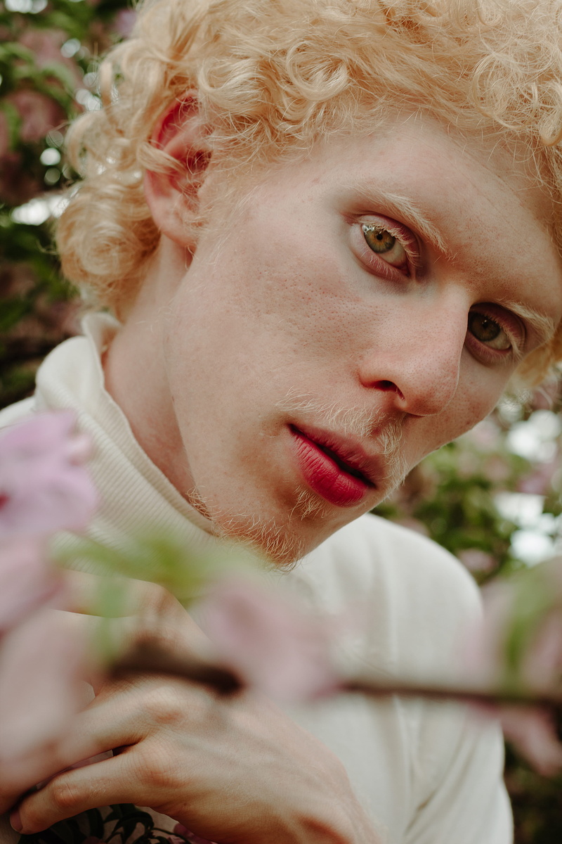 curly hair, man, contemplation, outdoors, blond, looking away, blonde, flower, face, beautiful woman, plant, hair, selective focus, portrait, flowering plant