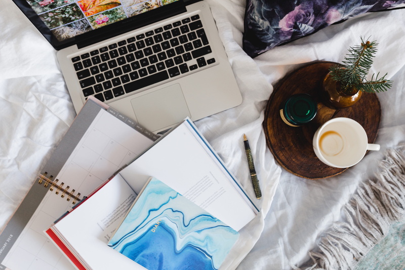 high angle view, table, computer, communication, laptop, food and drink, publication, using laptop, diary, coffee, furniture, notebook, indoors, pillows