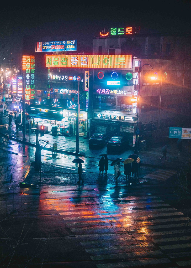 building exterior, wet, person, neon, light, land vehicle, asphalt, people, built structure, metropolis, illuminated, mode of transportation, architecture