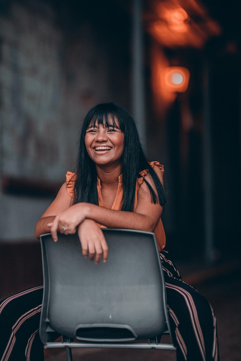 photoshoot, front view, urban, city, focus on foreground, person, adult, sitting, wear, woman, girl, plastic, one person, pose, portrait, young adult, facial expression