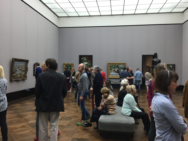 real people, museum, rear view, indoors, full length, 2K, berlin, large group of people, sitting, casual clothing, screen, projection screen, group, lifestyles