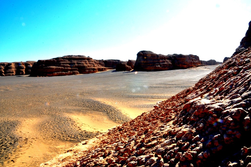 land, rock, beach, clear sky, sunlight, blue sky, water, solid, beauty in nature, nature, rock formation, outdoors, tranquil scene, arid climate, less traveled