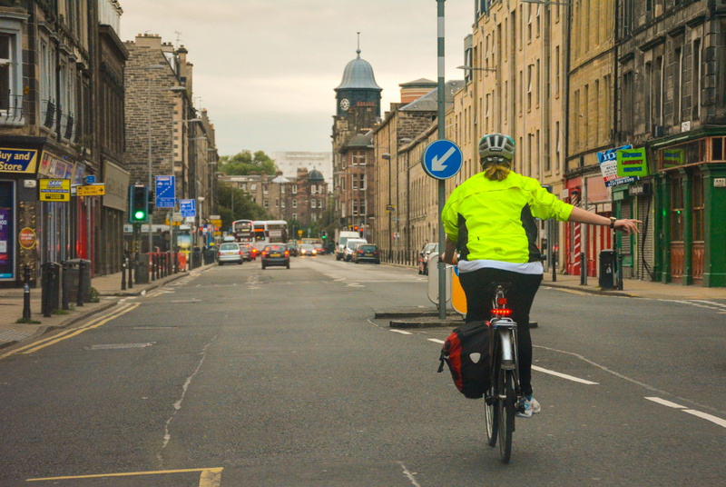 riding, cycle, city life, traffic, land vehicle, lifestyles, real people, street, outdoors, bicycle, cyclist, one person, cycling, men, rear view, sign