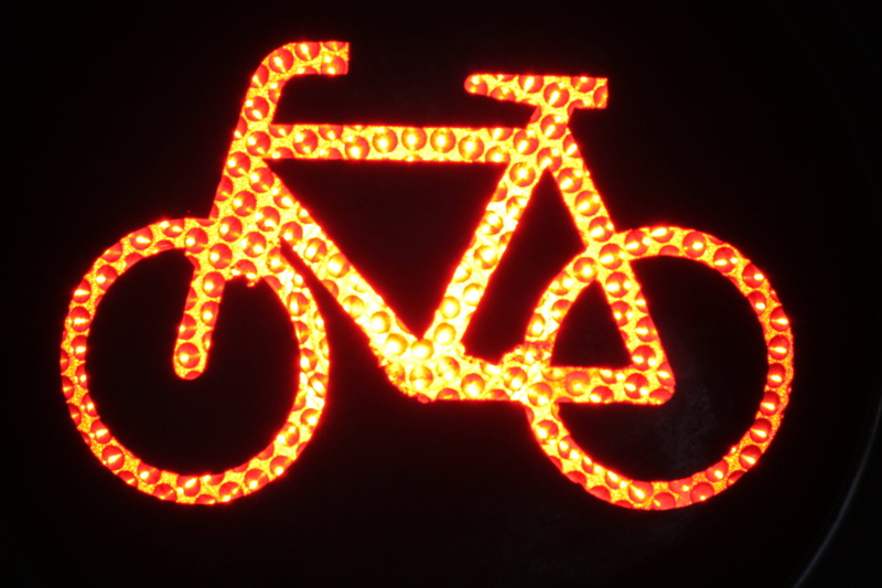 cyclists, road, glowing, traffic, close-up, red, no people, orthographic symbol, black background, single word, outdoors, neon, light signal, traffic lights