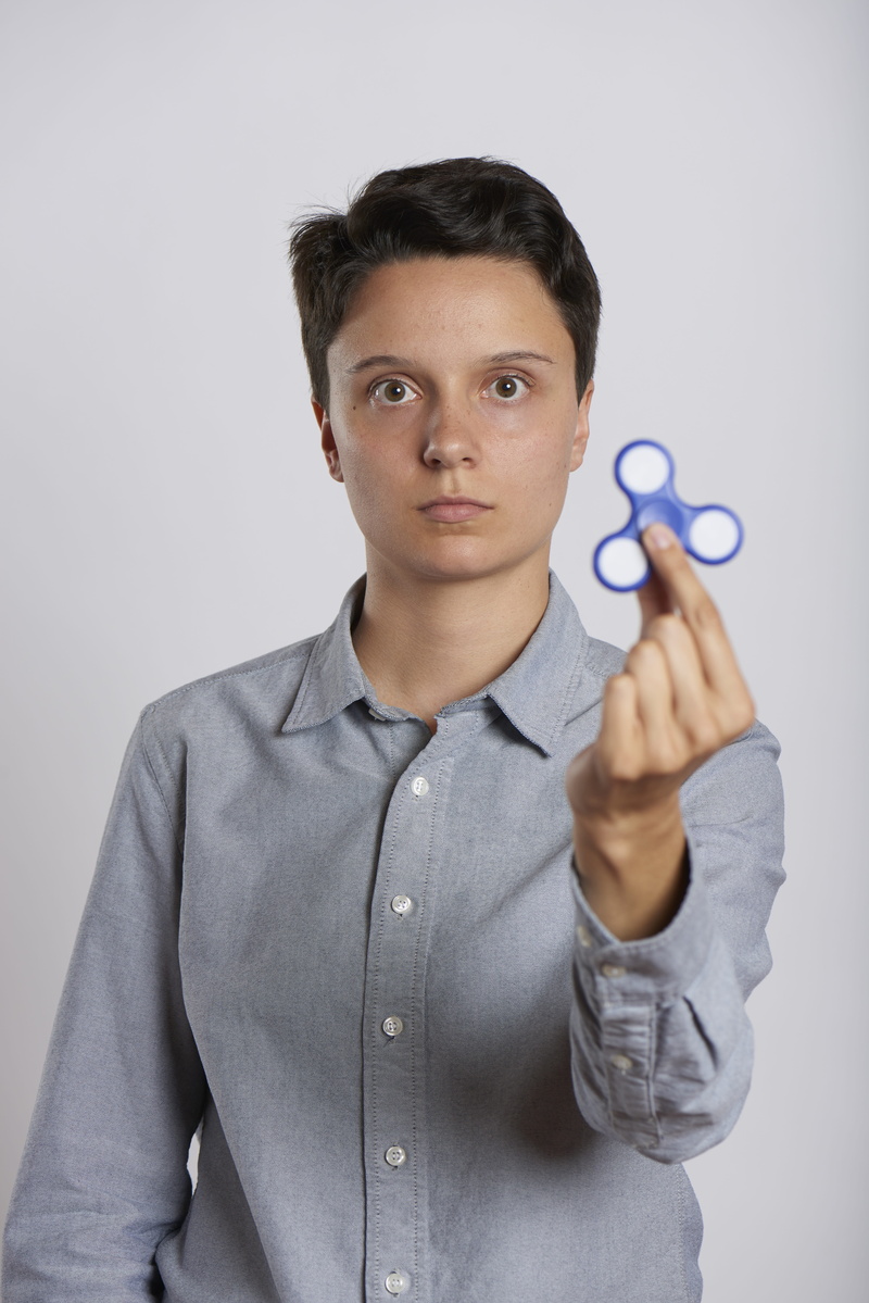 gadget, hyperactivity, fad, distraction, well-dressed, holding, gray, fidget spinner, indoors, game, front view, one person, looking at camera, fidget