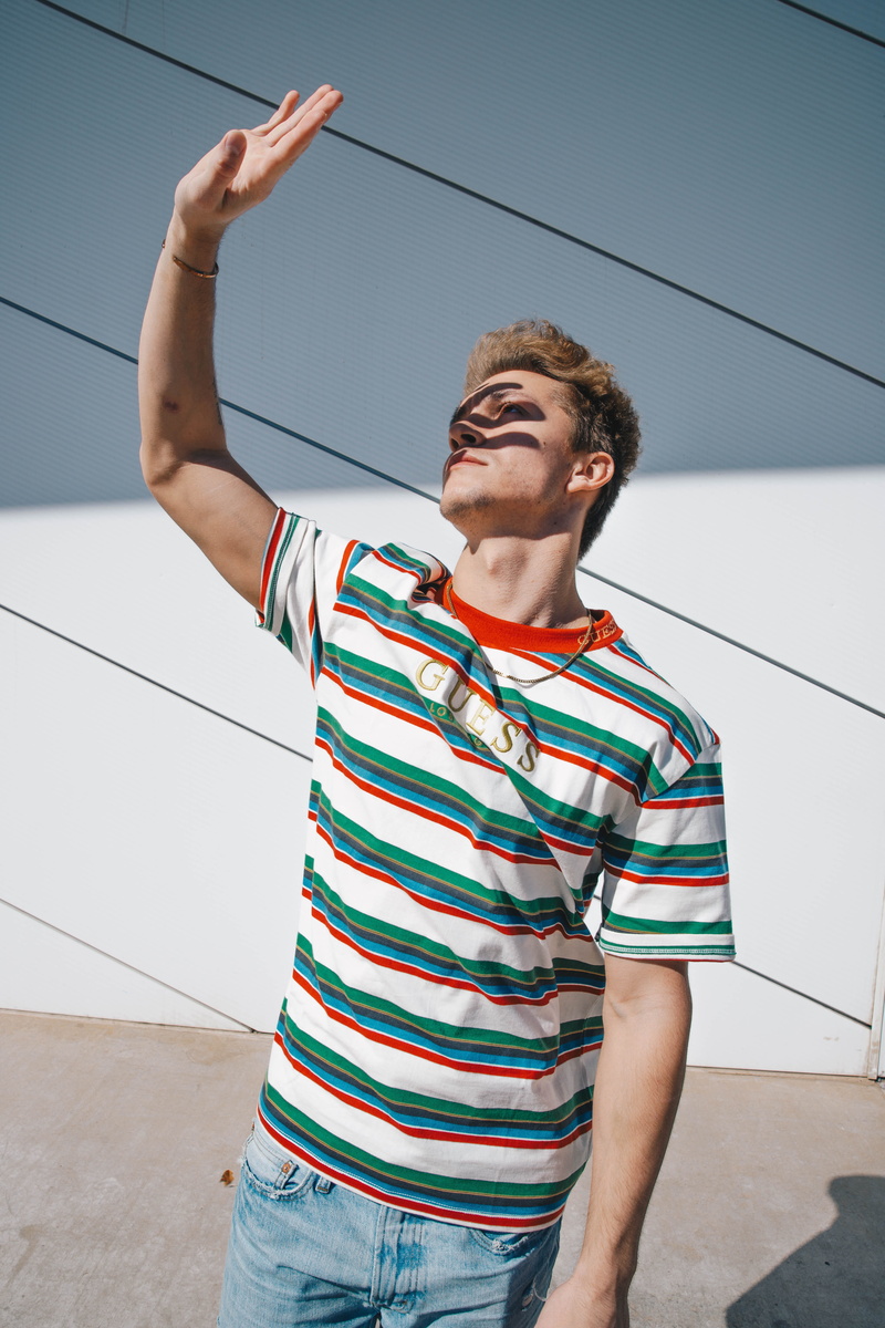 standing, leisure activity, wall - building feature, archery, slingshot, sport, human, 5K, shirt, right, day, three quarter length, symbol, clothing, teenager