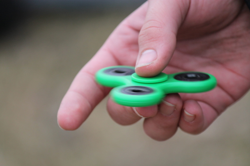 holding, single object, finger, hand, outdoors, childhood, green color, human finger, toy, spin, body part, studio shot, human hand, care, mental health