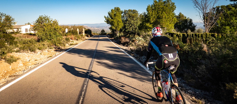 person, apparel, mode of transportation, day, clothing, rear view, shadow, daytime, 5K, helmet, headwear, machine, vehicle, cycling, sports, riding, ride