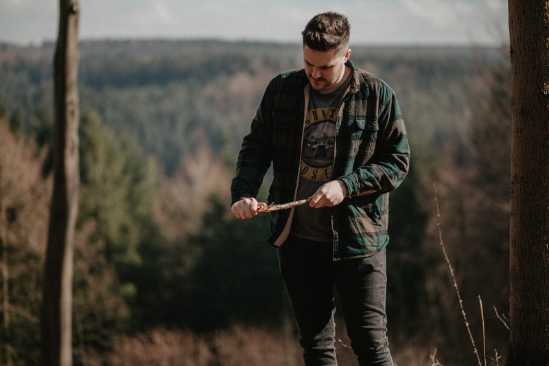 whittling, grass, green, adult, twig, looking, stick, outdoors, daytime, shallow, near, male, field, standing, aggression, young adult, forest, man, leafed