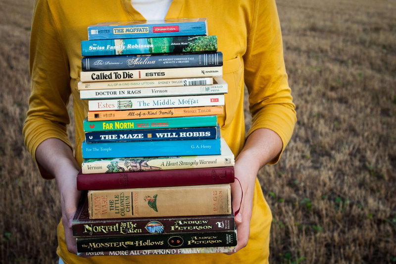 one person, midsection, reading, nonfiction, 2K, female, day, nature, text, classics, hand, novel, biography, holding, book, book stack, small group of objects