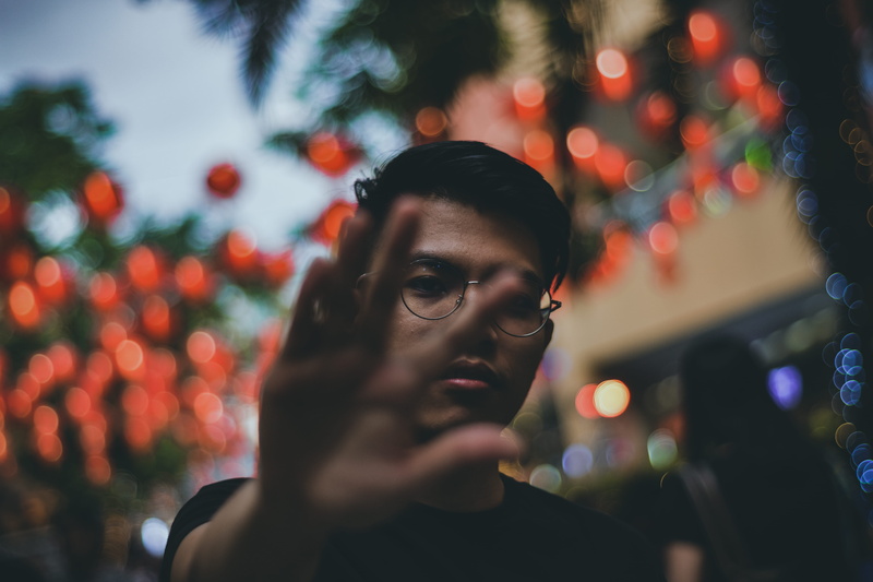 night, streetwear, contemplation, male, menswear, real people, reaching, one person, adult, blurred background, facial expression, hair, leisure activity