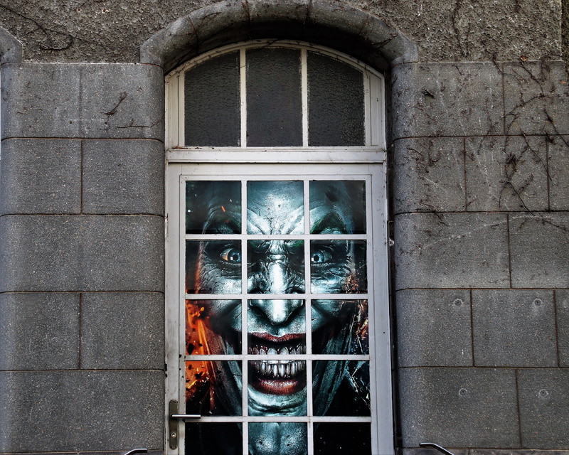 outdoors, one animal, clown, window, representation, the walls of the, built structure, the structure of the, gray, looking at camera, pane, wall - building feature