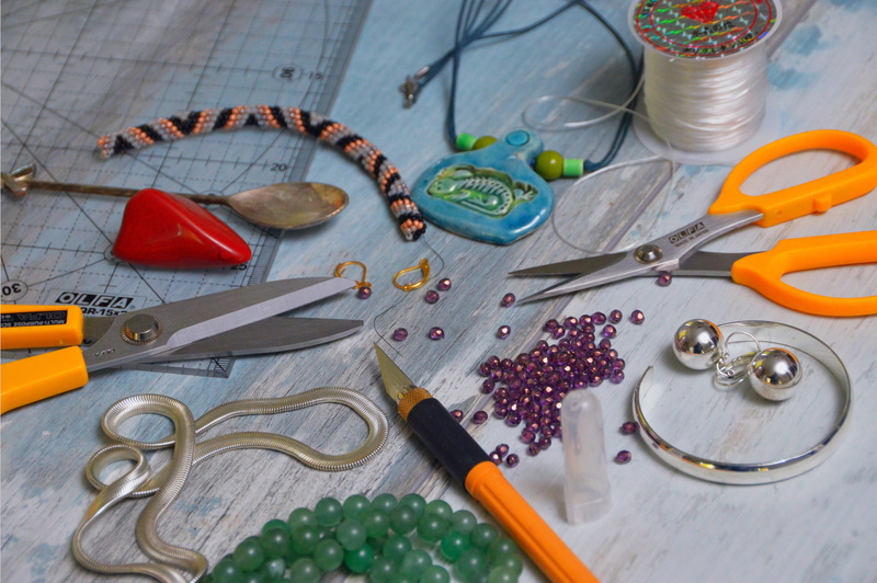 large group of objects, paintbrush, hand tool, table, tool, still life, silver chain, indoors, textile, patchwork, metal, close-up, necklace, tools, brush
