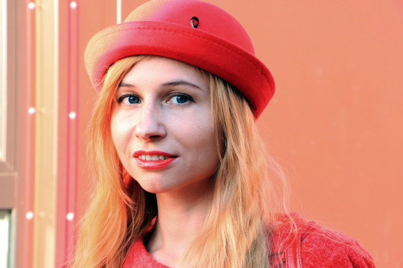 red hat, hairstyle, blond hair, bowler hat, woman in hat, colored background, looking at camera, human face, hair, portrait, hat, young adult, photo portrait