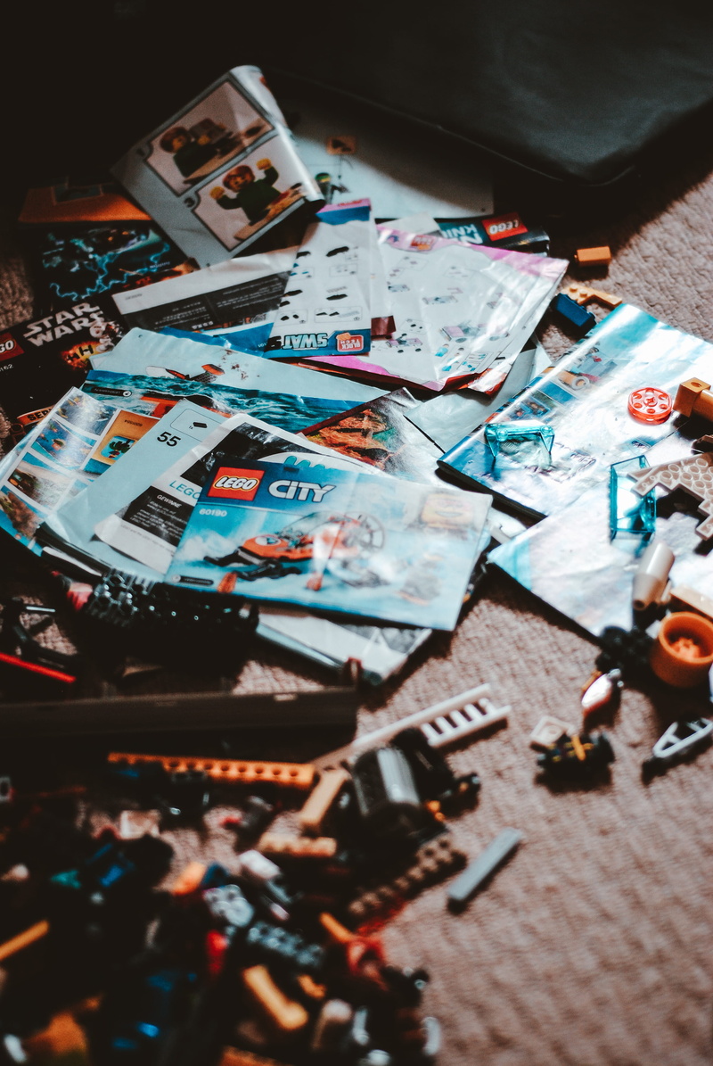 selective focus, indoors, brochure, 4K, toy, people, still life, text, close-up, lot, human representation, lego, paper, multi colored, console, human