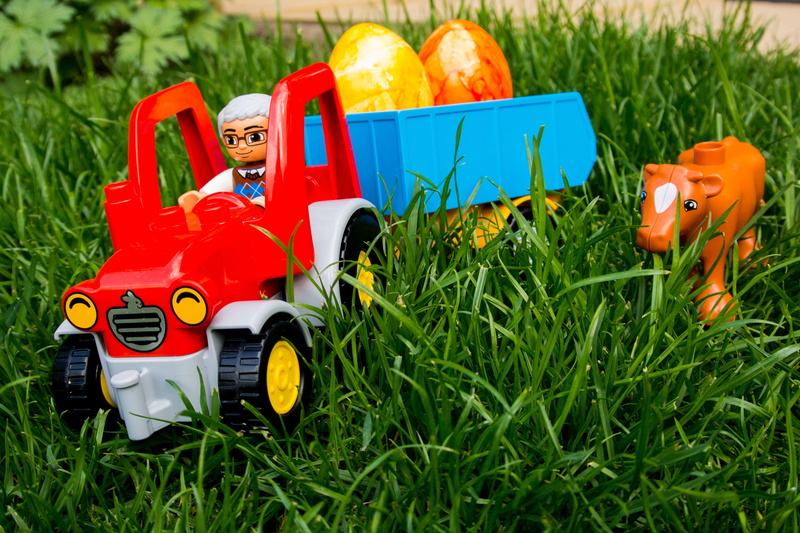 toy car, multi colored, plant, childhood, still life, tractor, red, outdoors, land, spring, easter, cow, close-up, representation, colored, field, toy