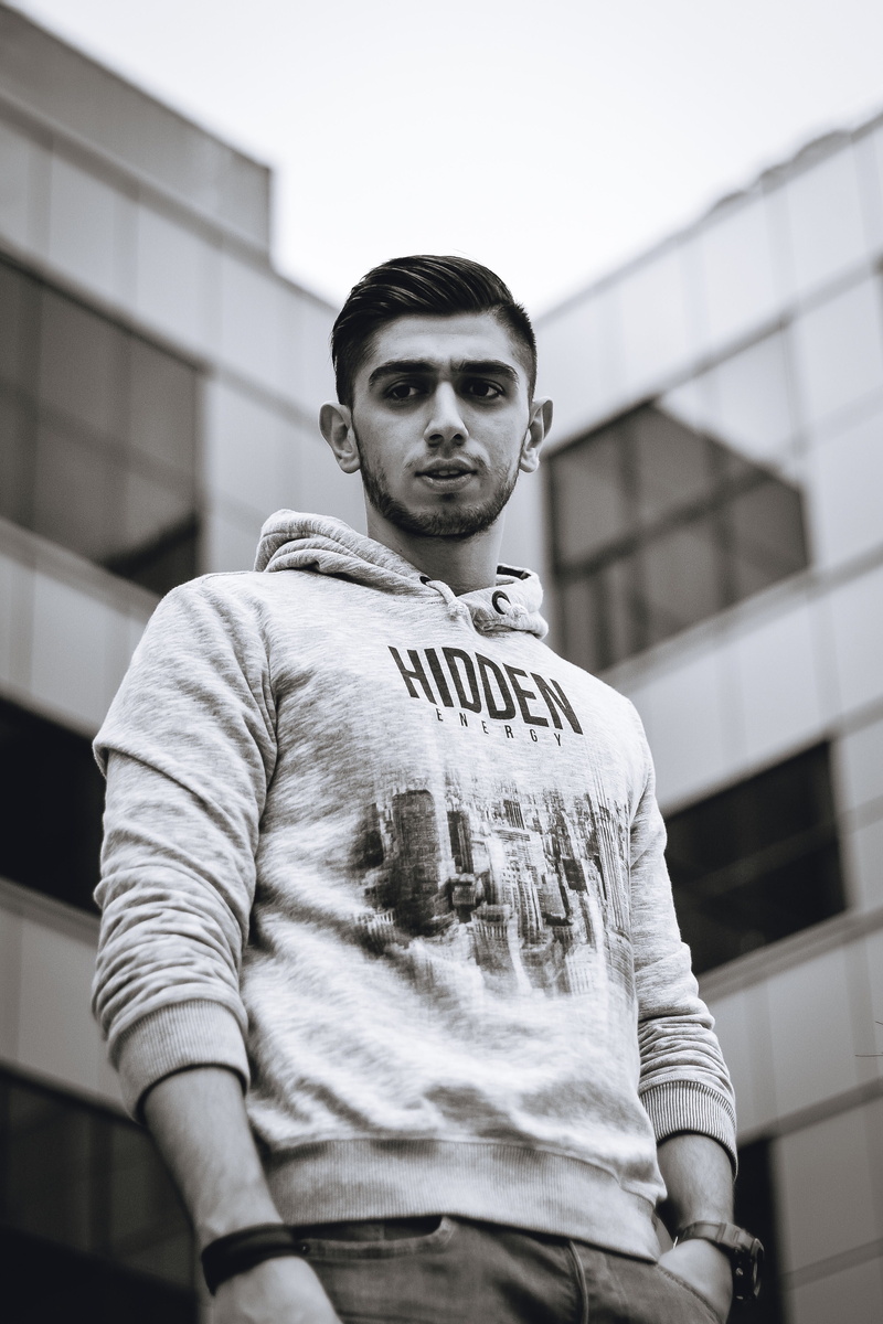 beanie, looking at camera, sleeve, lifestyles, apparel, hoodie, portrait, clothing, day, hood, tower, long sleeve, low angle view, building, leisure activity